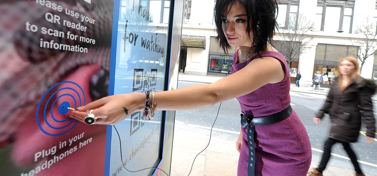 Interactive bus stop installed by Plan UK on London's Oxford Street for its ‘Because I am a Girl” campaign, 2014. Photograph by Anthony Devlin / PA. This bus stop distinguishes the gender of the viewer and delivers different information to men and women about the unequal opportunities enjoyed by girls in the developing world. 